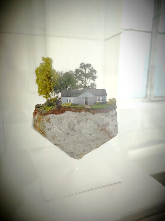Miniatura de casa sobre un fragmento de roca